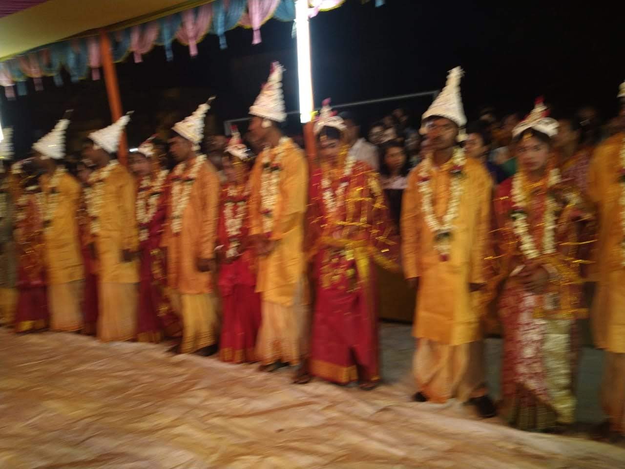 Couples standing together in wedding attire at a community marriage ceremony